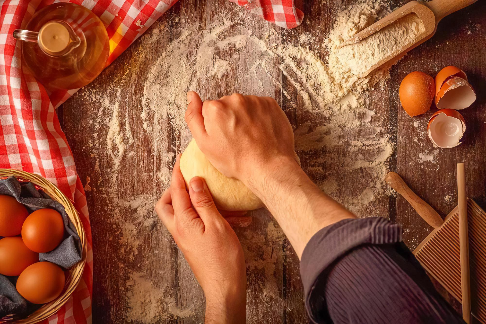Close-up of hands kneading dough on wooden board